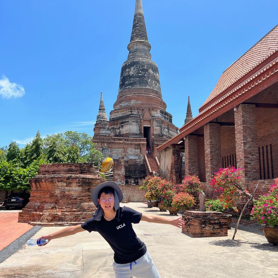 Ethan striking a pose in front of a tall brick stupa at an ancient temple in Ayutthaya