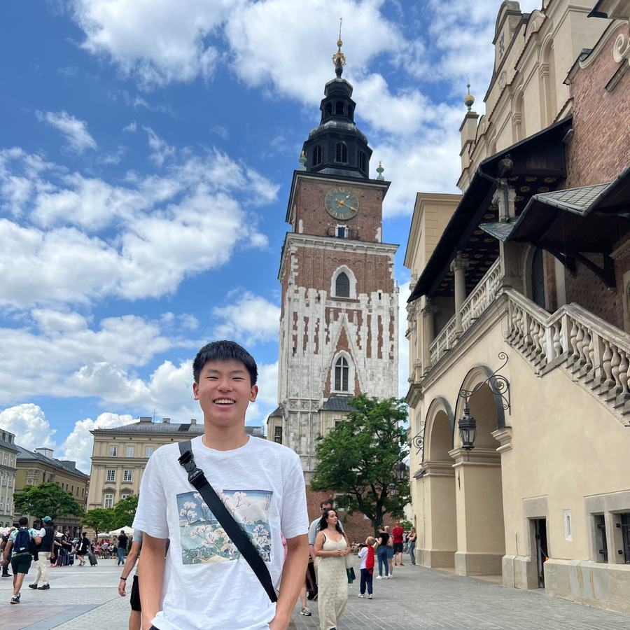 Ethan smiling in Kraków's Main Market Square, in front of the Town Hall Tower