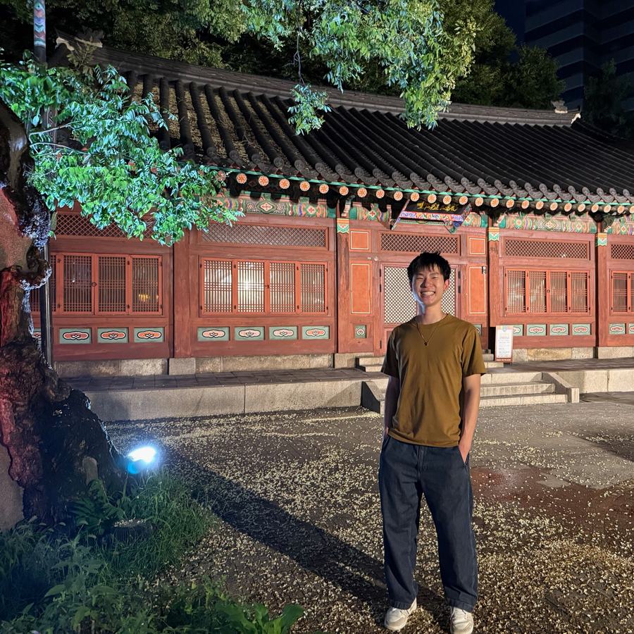 Ethan standing in front of a traditional Korean hanok building lit up at night in Seoul