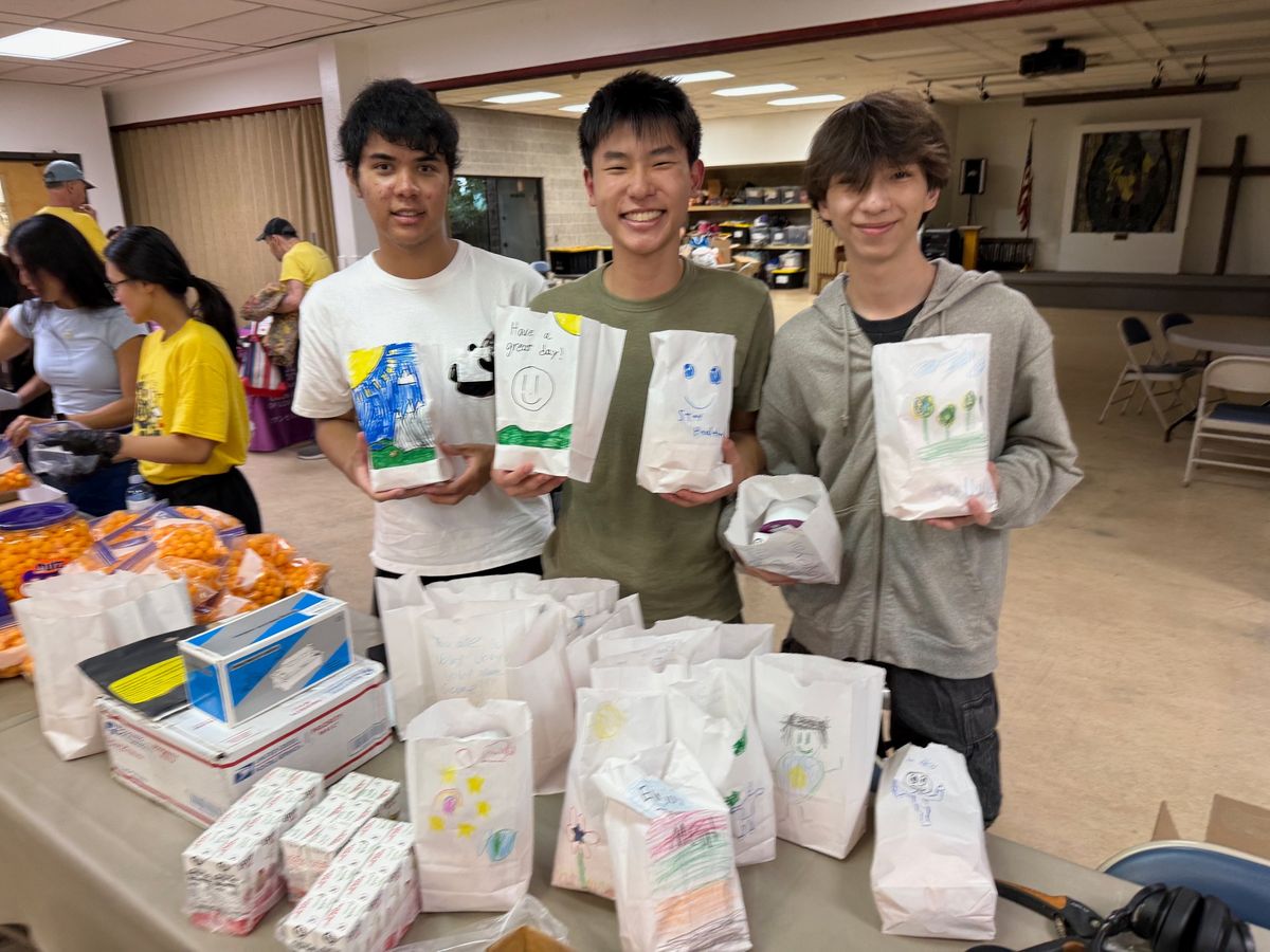 Ethan and two friends holding up meal bags decorated with children's drawings and messages like Have a great day