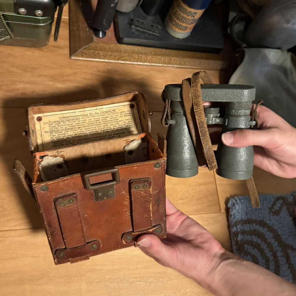 Ethan holding military binoculars next to their open leather case, which has instructions printed inside the lid
