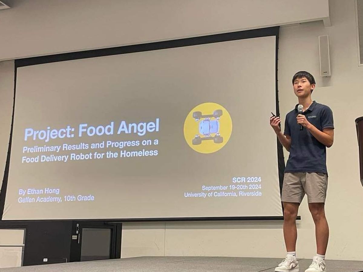 Ethan on stage with a microphone beside a slide titled Project Food Angel, SCR 2024