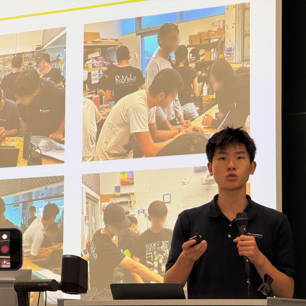 Ethan presenting photos of high school students building robots in the Q8Bot workshop at UR2026