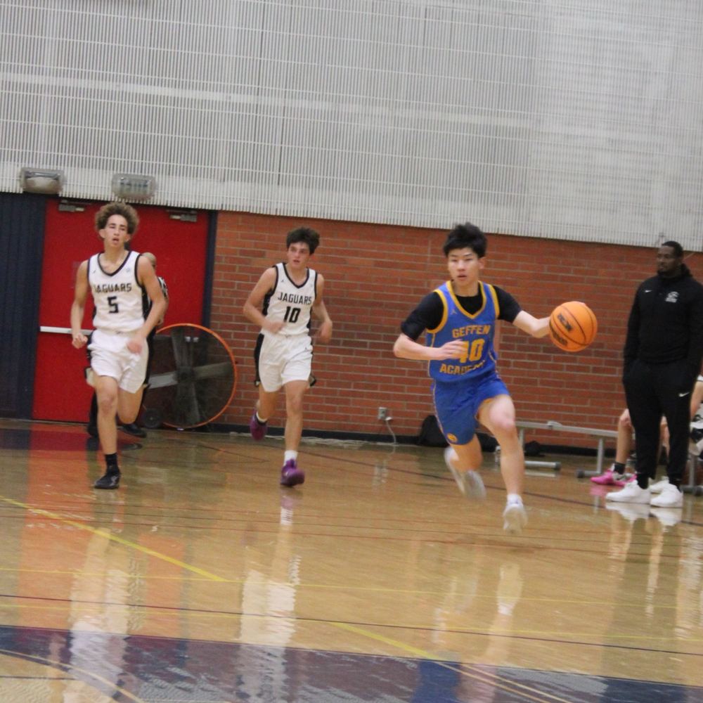 Ethan dribbling up the court on a fast break ahead of two defenders