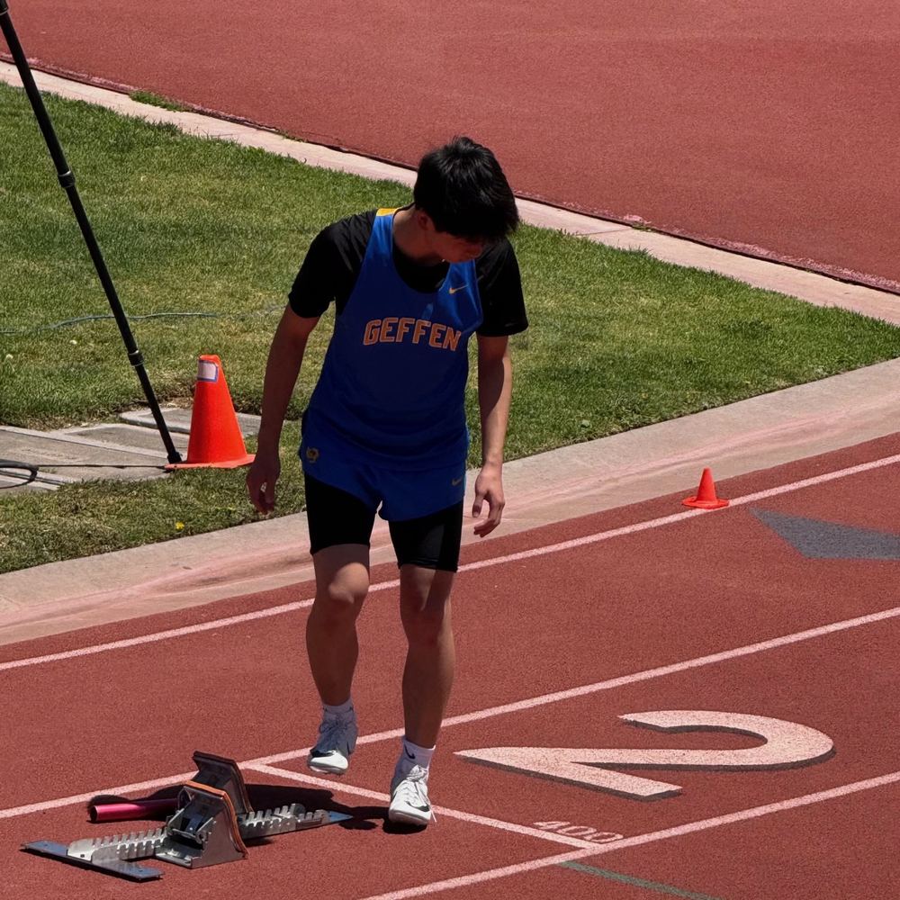 Ethan in a Geffen singlet stepping into the starting blocks in lane 2