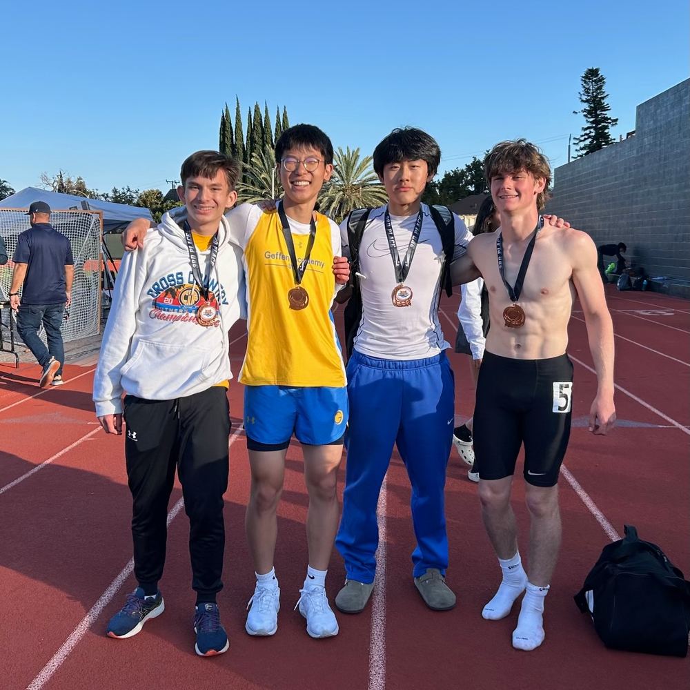 Ethan and three teammates standing on the track with their medals