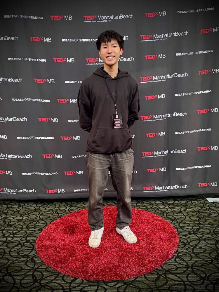 Ethan standing on the red circle in front of the TEDxManhattanBeach backdrop